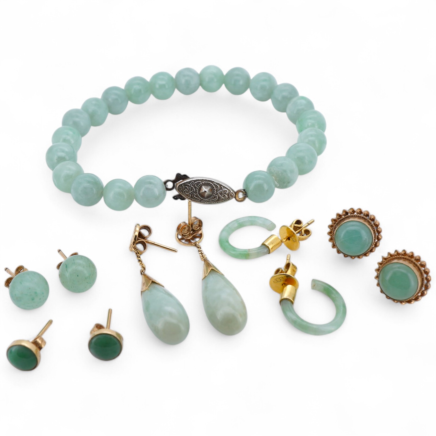 A collection of jadeite jewels, comprising: a bead bracelet with a silver clasp; together with three pairs of studs; one pair of hoop studs, one broken and restuck; and one pair of drop earrings, each set with jadeite, m